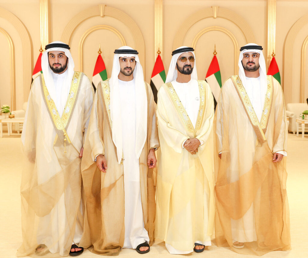 الشيخ حمدان بن محمد بن راشد آل مكتوم (الثاني من اليسار)، ولي عهد دبي، وشقيقه الشيخ مكتوم (الأول من اليمين) يتوسطان والدهما حاكم دبي