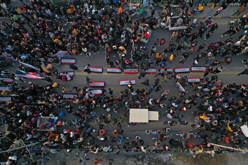 An aerial view shows Iraqis, carrying posters of killed anti-government protesters, attend a march to honour the memory of the…